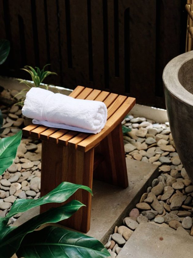 The Zapatera Stool by Masaya & Co placed with a rolled towel on top of it in an outdoor bath setting
