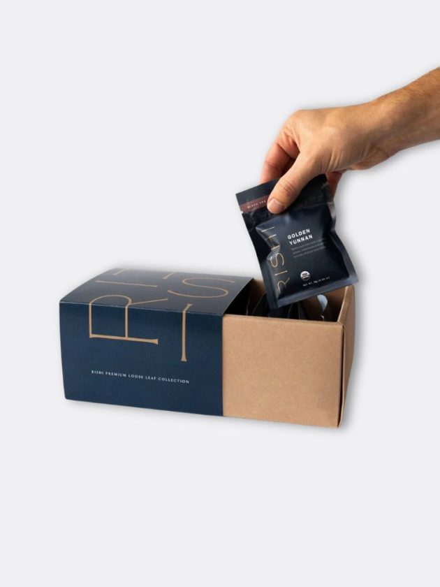 A hand reaching for a pack of ethically sourced loose leaf teas from the premium loose-leaf gift set by Rishi Tea & Botanicals