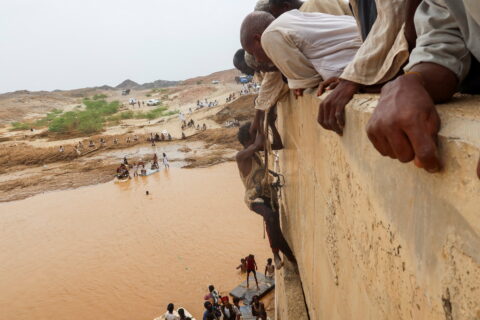 A survivor harnessed to a rope is helped to climb a wall, following devastating floods, in South Tokar, Red Sea State, Suda