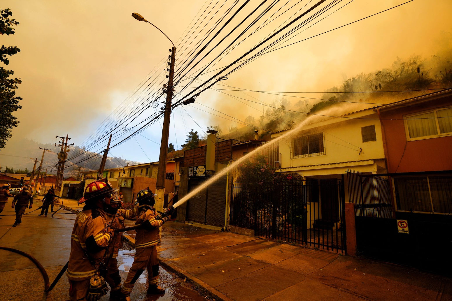 Firefighters spray water on homes in Vina del Mar, Chile. 