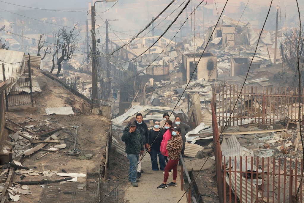 Inhabitants of Lirquen, in Chile, walk through the homes consumed by the flames in January 2026. Credit: UNAR Photo / Alamy Stock Photo.