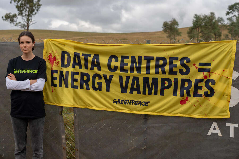 Greenpeace activists and local community members protest at the proposed Mamre Rd Data Centre. Greenpeace campaigner Solaye Snider at the site of the proposed Mamre Rd data centre with a banner saying "Data centres = energy vampires"