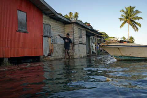 Local boy Ratusela Waqanaceva wades through seawater flooding over an ineffective sea wall at high tide, as the community experiences flooding in Serua Village, Fiji