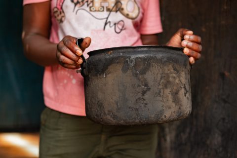 A woman holds a cooking pot covered in soot that she uses on the open fire in Nairobi, Kenya.