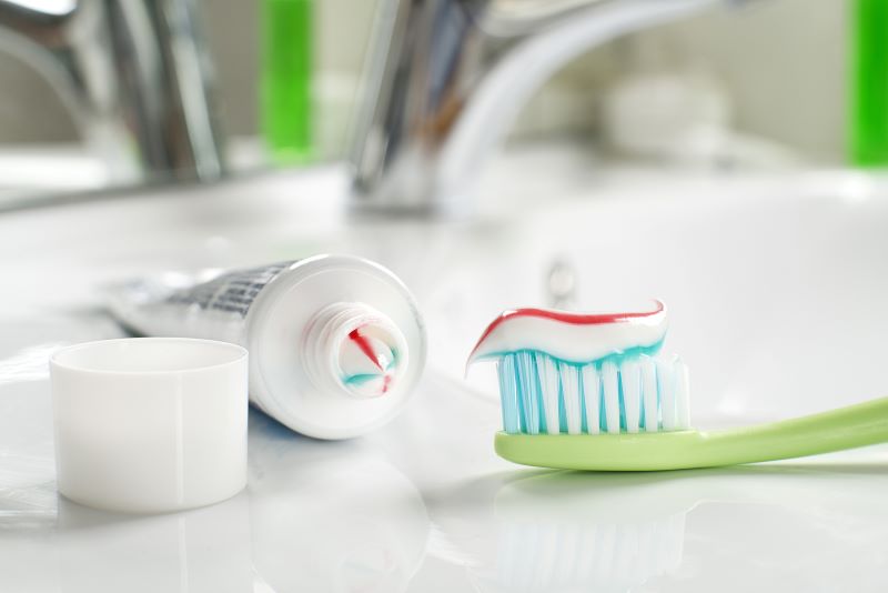toothpaste on toothbrush on sink