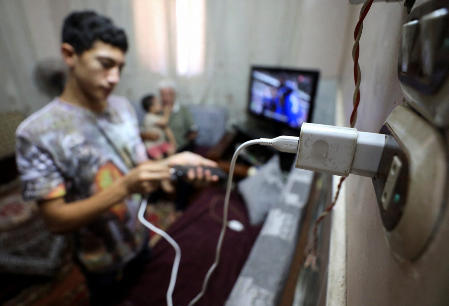 A man charges his mobile phone thanks to the electric solar panels above his as the country struggled with continuous power cuts and an energy crisis in 2024