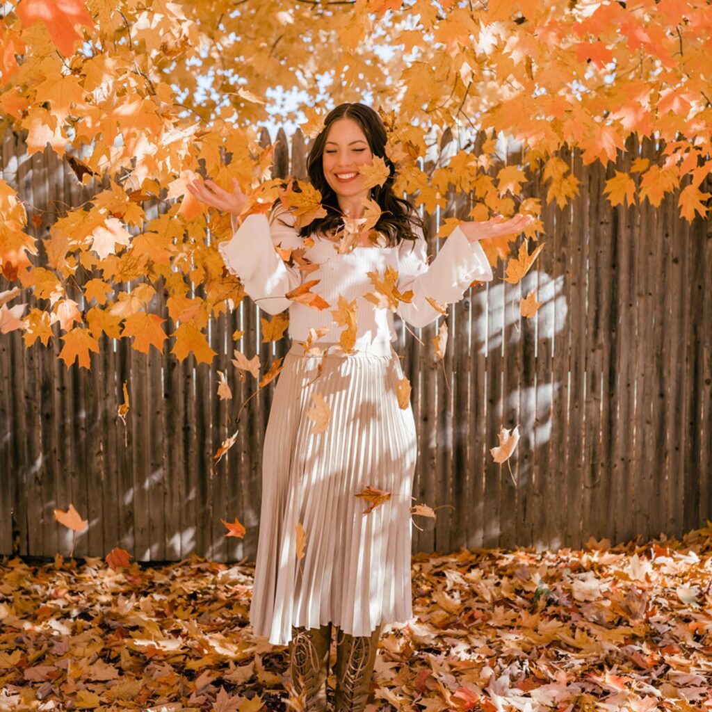 Kathryn Kellogg tossing fall leaves in the air