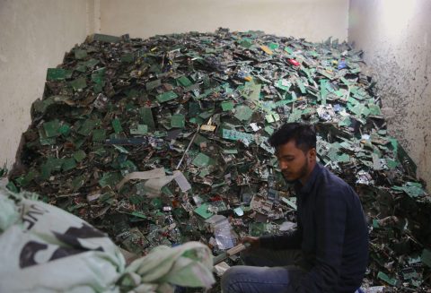 A man sits in front of a pile of electronic waste at the Seelampur e-market in New Delhi, India (Photo: Cheena Kapoor)
