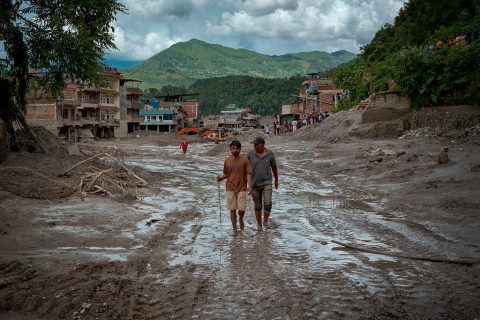 Residents walk along a muddy road following flash floods on August 27, 2026 in Trishuli, Nepal.