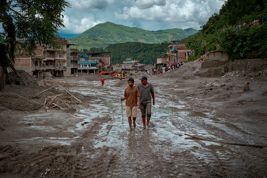 Residents walk along a muddy road following flash floods on August 27, 2026 in Trishuli, Nepal.