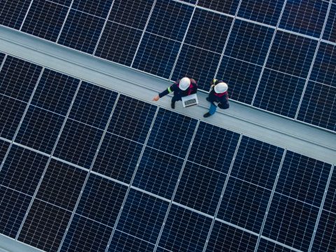 Aerial view of two workers checking solar panel equipment