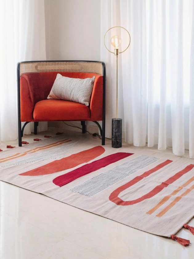 Printed rug and red chair with gold floor lamp